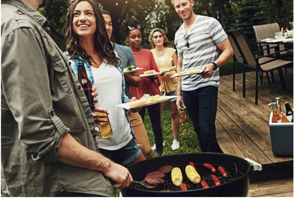 Group of friends socializing and grilling outdoors on a wooden deck.